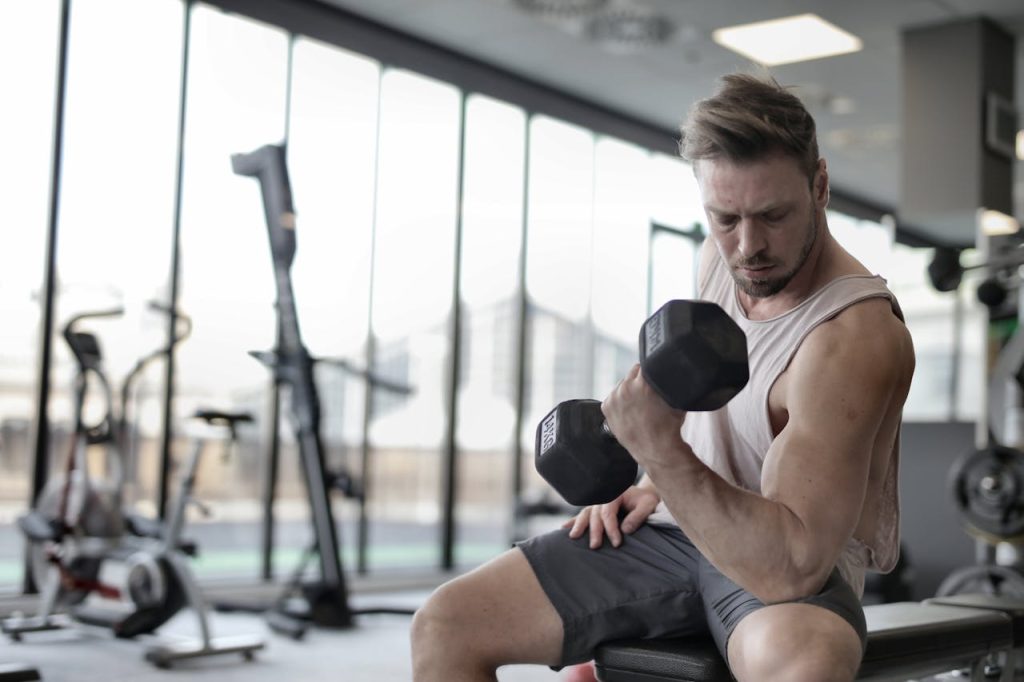 A man sitting on a gym bench performing a seated dumbbell bicep curl